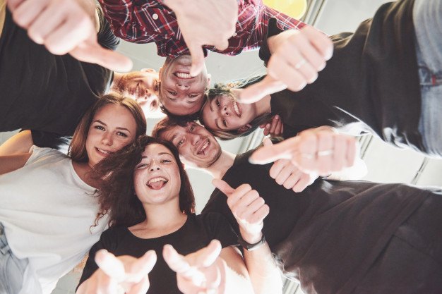 People in circle looking down at camera giving thumbs up